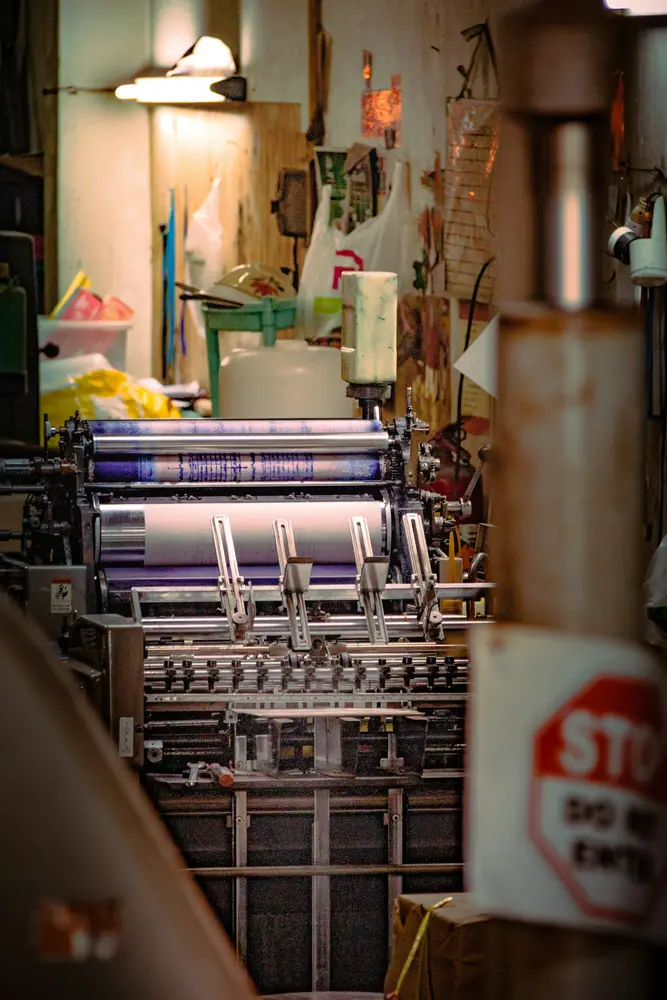 Offset printing press with ink rollers in a busy print shop